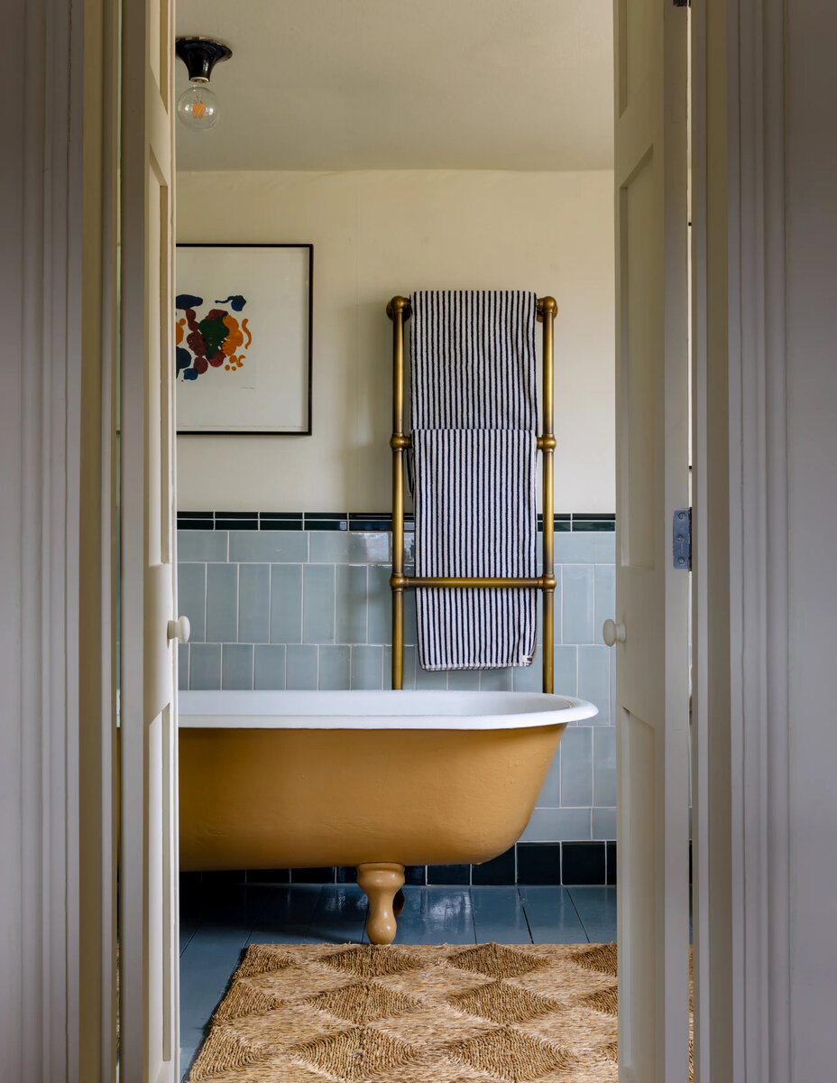 Те, кто ночует в гостевой комнате, имеют доступ к персональной ванной. Она чуть скромнее хозяйской, но тоже оформлена стильно. Обоев тут нет, зато желтая чугунная ванна на ножках смотрится идеально на фоне голубой плитки